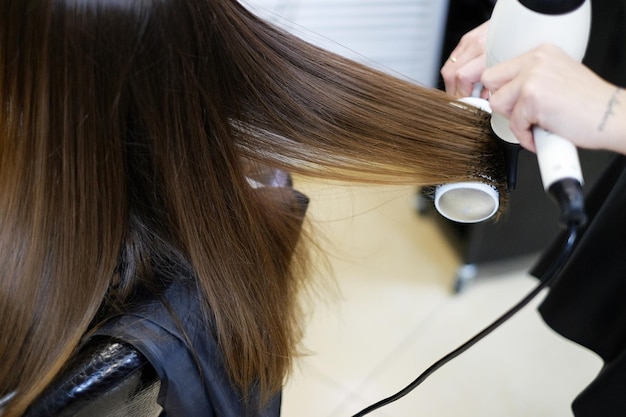 Парикмахер сушит волосы клиента в салоне крупным планом