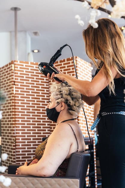 Hairdresser drying the hair of a customer giving a perm