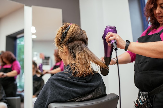 Parrucchiere che asciuga i capelli della donna