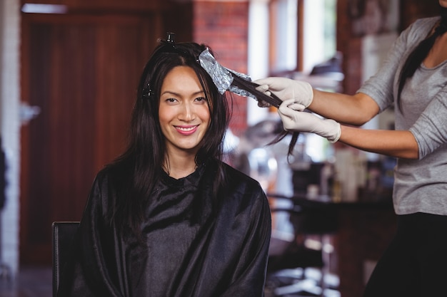 Hairdresser dyeing hair of her client