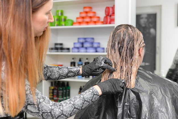 Photo the hairdresser dyes the hair of a woman in the salon.