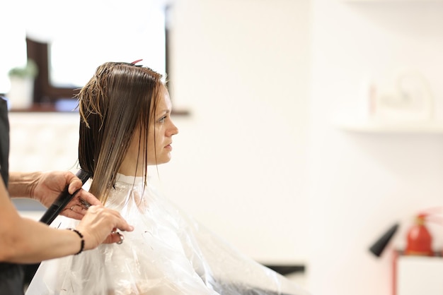 Hairdresser hands cut hair of client in beauty salon