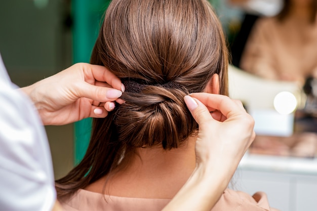 Hairdresser hands making hairdo.