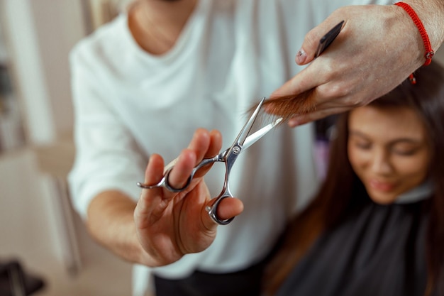 Hairdresser holding scissors in his hands and cutting client hair