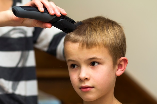 Hairdresser is cutting hair of a child boy in barber shop