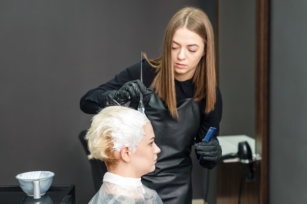 Hairdresser is dyeing female hair