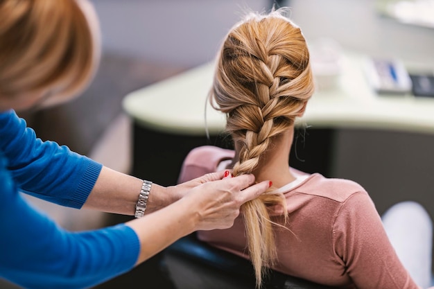 A hairdresser is making braid in a salon