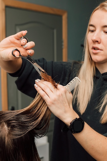 The hairdresser lifted a strand of hair up and cut off the length