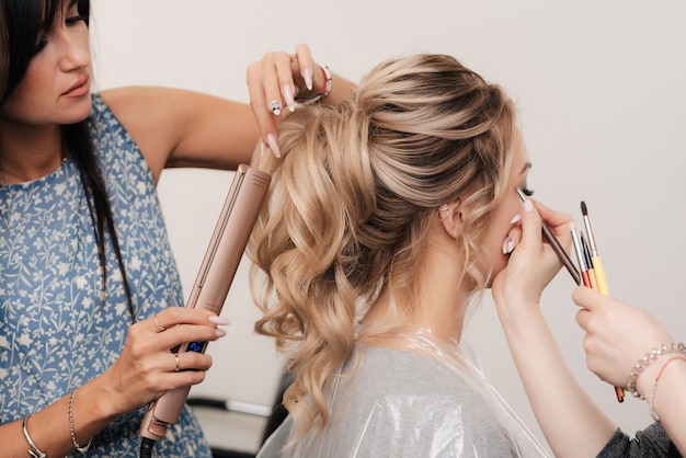 A hairdresser and a make-up artist together do their hair and make-up in a professional salon
