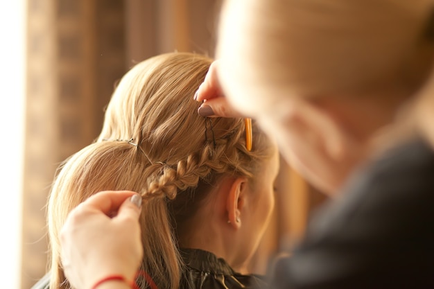 Hairdresser makes hairstyle for the bride