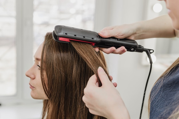 a hairdresser makes a hairstyle for a girl in a beauty salon. straighten your hair with an iron