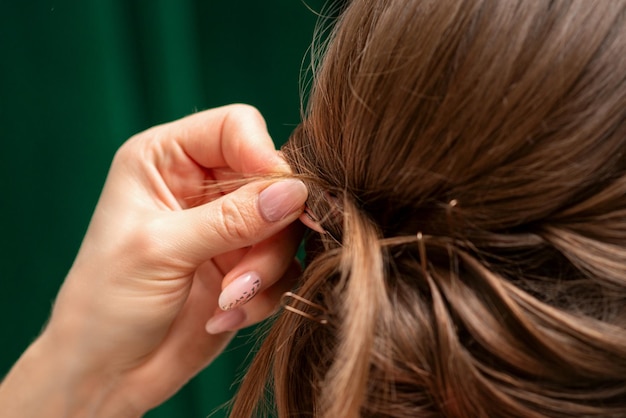 Hairdresser makes hairstyles for a young woman in beauty salon close up.