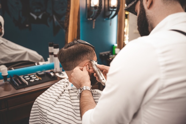 Hairdresser makes a machine haircut for the client