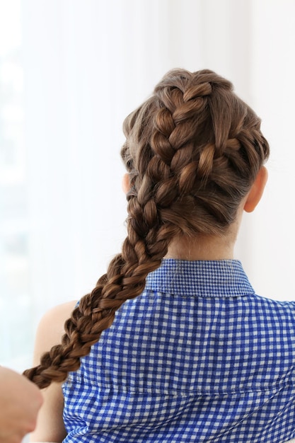 Hairdresser making braid hairstyle to young beautiful woman closeup