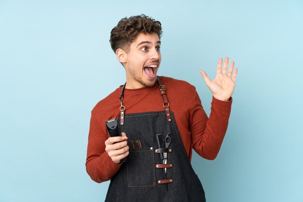 Hairdresser man on blue with surprise facial expression