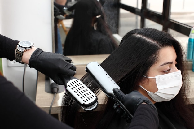 Photo hairdresser in a medical mask works in the salon