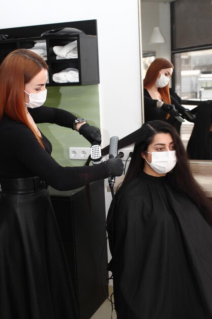 Hairdresser in a medical mask works in the salon