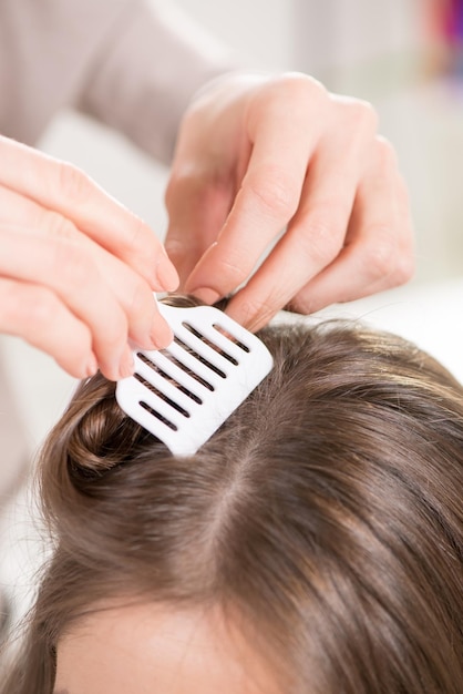 Hairdresser putting hair Clips on a woman hair. Close-up.