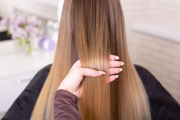 hairdresser's hand brushing long natural blonde hair in beauty salon