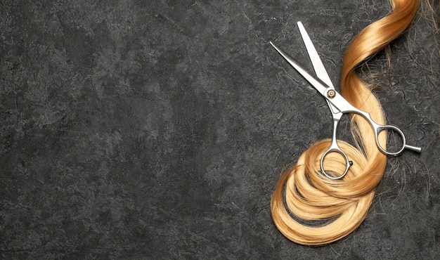 Il parrucchiere. forbici e ricciolo di capelli su un nero.