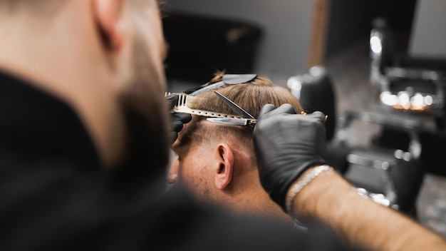 Hairdresser scissors hair on the head sides for a stylish blackhaired man in the barbershop