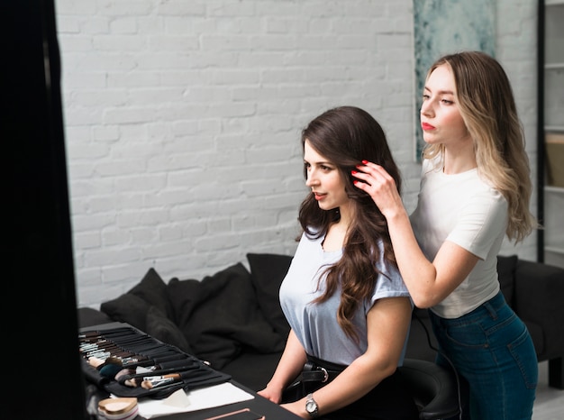 Hairdresser setting hairstyle of young female client