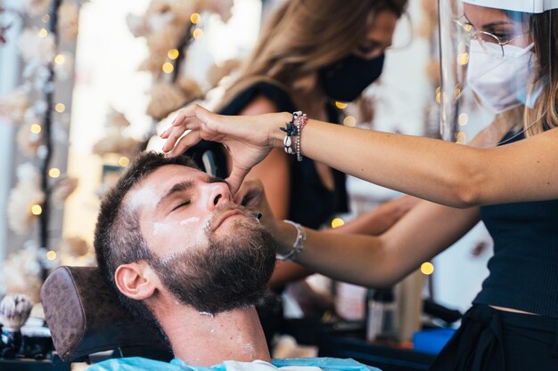 Hairdresser shaving a client in a barbershop