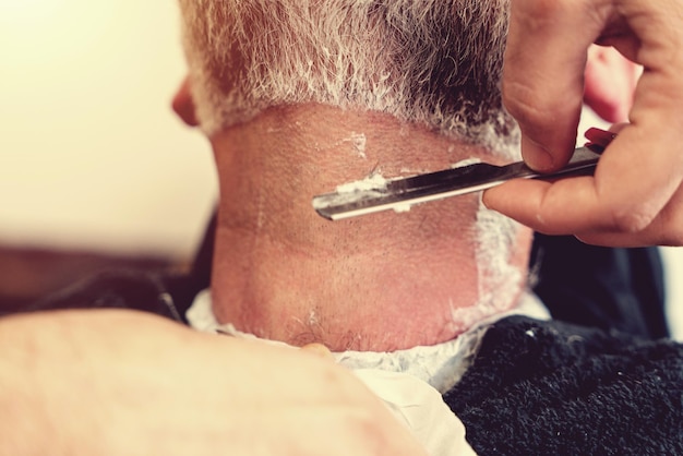 Hairdresser shaving man\'s neck with a straight razor