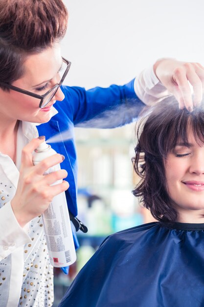 Hairdresser styling woman hair in shop