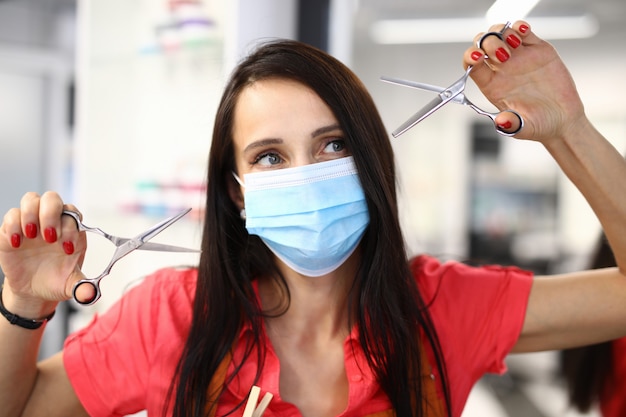 Hairdresser stylist in protective mask holds scissors in his hands