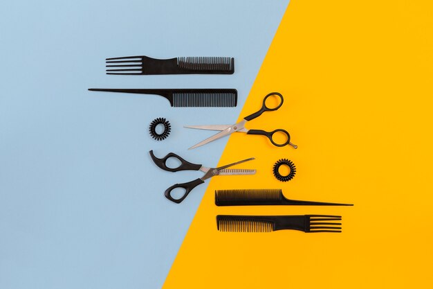 Hairdresser tools on blue and yellow background with copy space top view flat lay