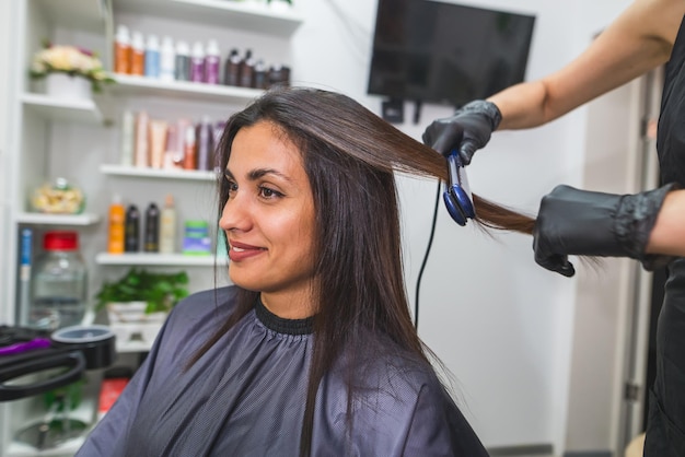 Hairdresser using a hair straightened to straighten the hair Hair stylist working on a woman's hair style at salonHair care Beautiful attractive woman in a beauty salon