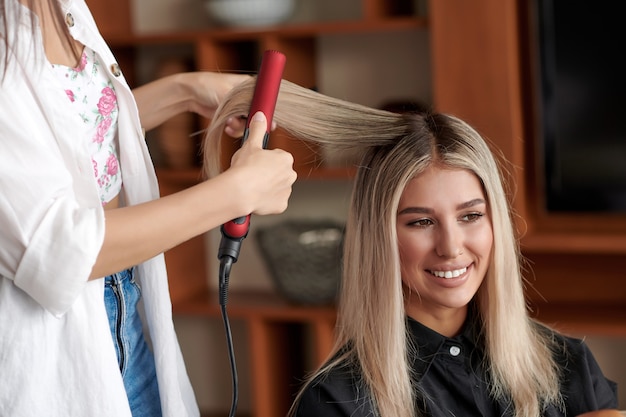 Hairdresser using a hair straightener at salon