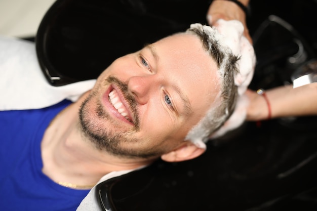 Hairdresser washing head of a young man in sink