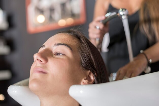 Hairdresser washing woman hair