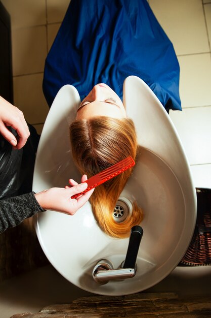 Hairdresser washing young woman's hair in salon. Hair care.