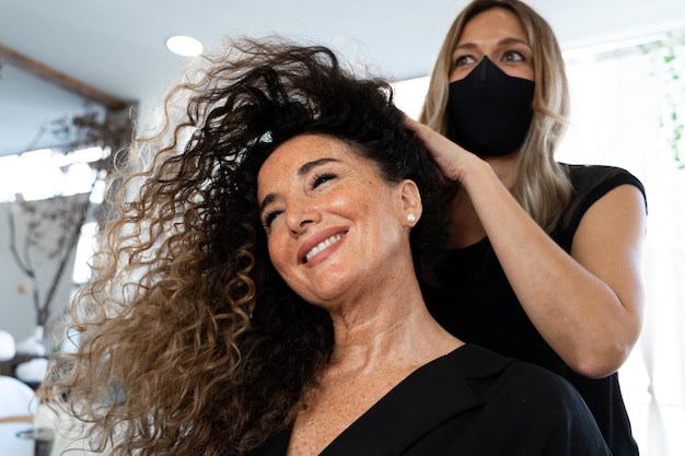 Hairdresser wit facial mask massaging the hair of a client in a salon