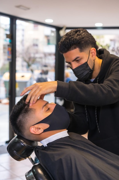 Hairdresser with face mask finishing the cut to the client