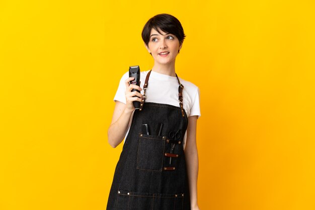 Hairdresser woman isolated on yellow space thinking an idea while looking up