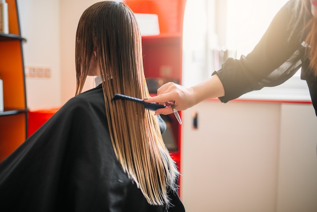 Photo hairdresser works with spray, female hairdressing