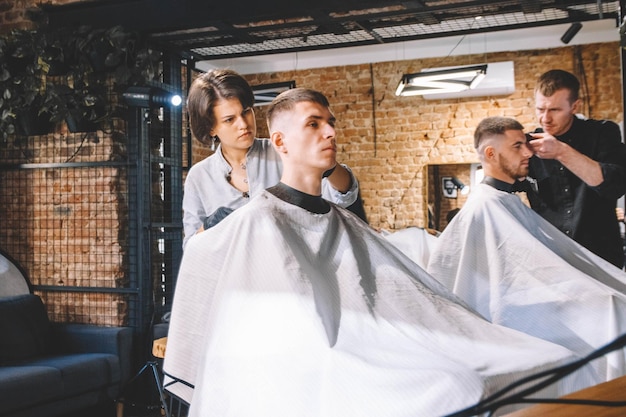 Hairdressers cut their clients in barbershop. Advertising and barber shop concept