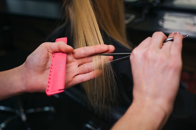 hairdressers hand cutting blonde hair