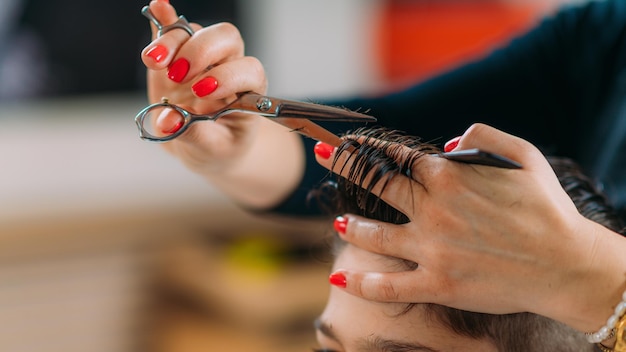 hairdressers hands cutting boy's hair in salon