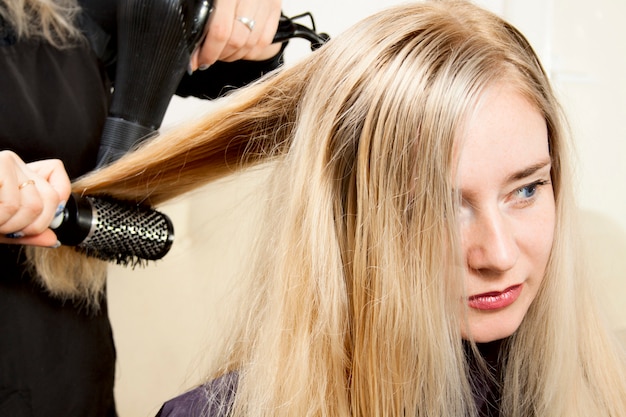 Hairdressers hands drying long blond hair