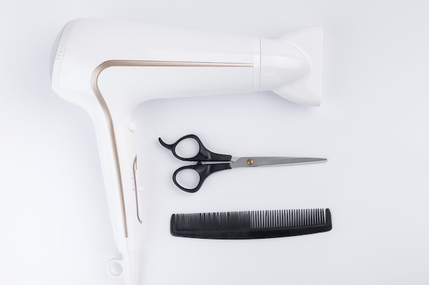 Hairdryer for drying hair scissors and comb on a white background Top view