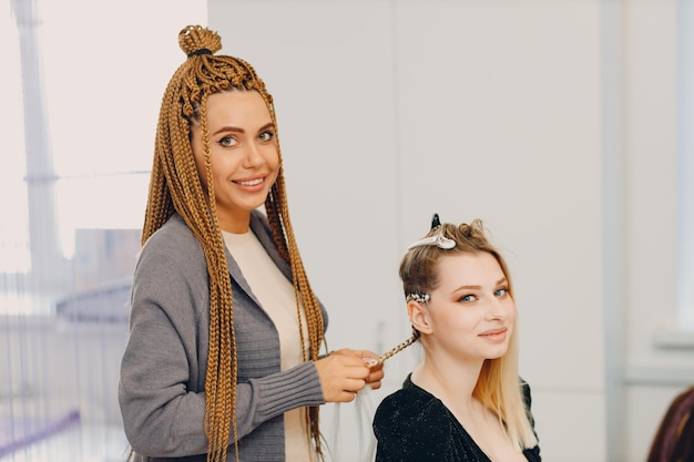 Hairstylist braided afro braids pigtails hair of female client in barber salon