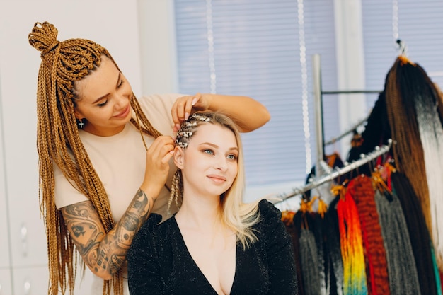 Hairstylist braided afro braids pigtails hair of female client in barber salon