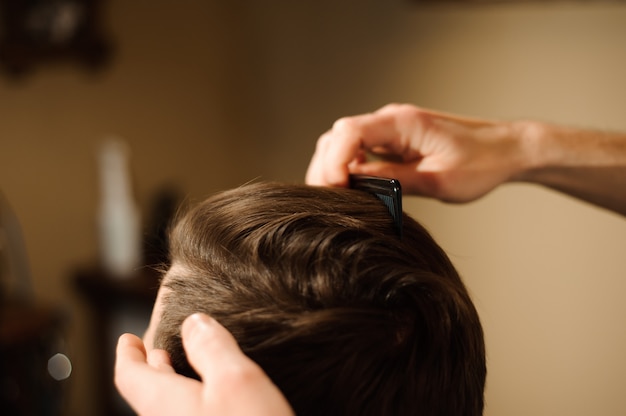 Hairstylist cuts hair and beard of man in the barbershop