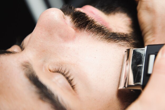 Hairstylist cuts hair and beard of man in the barbershop