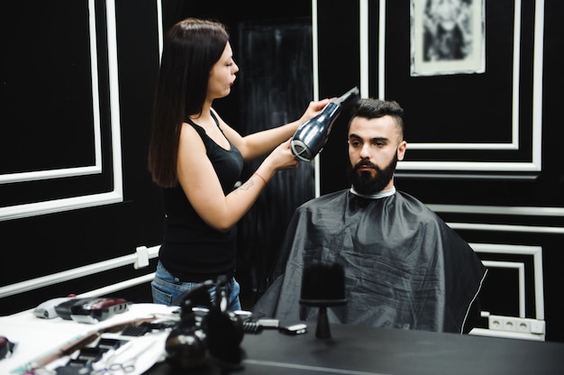 Hairstylist cuts hair and beard of man in the barbershop